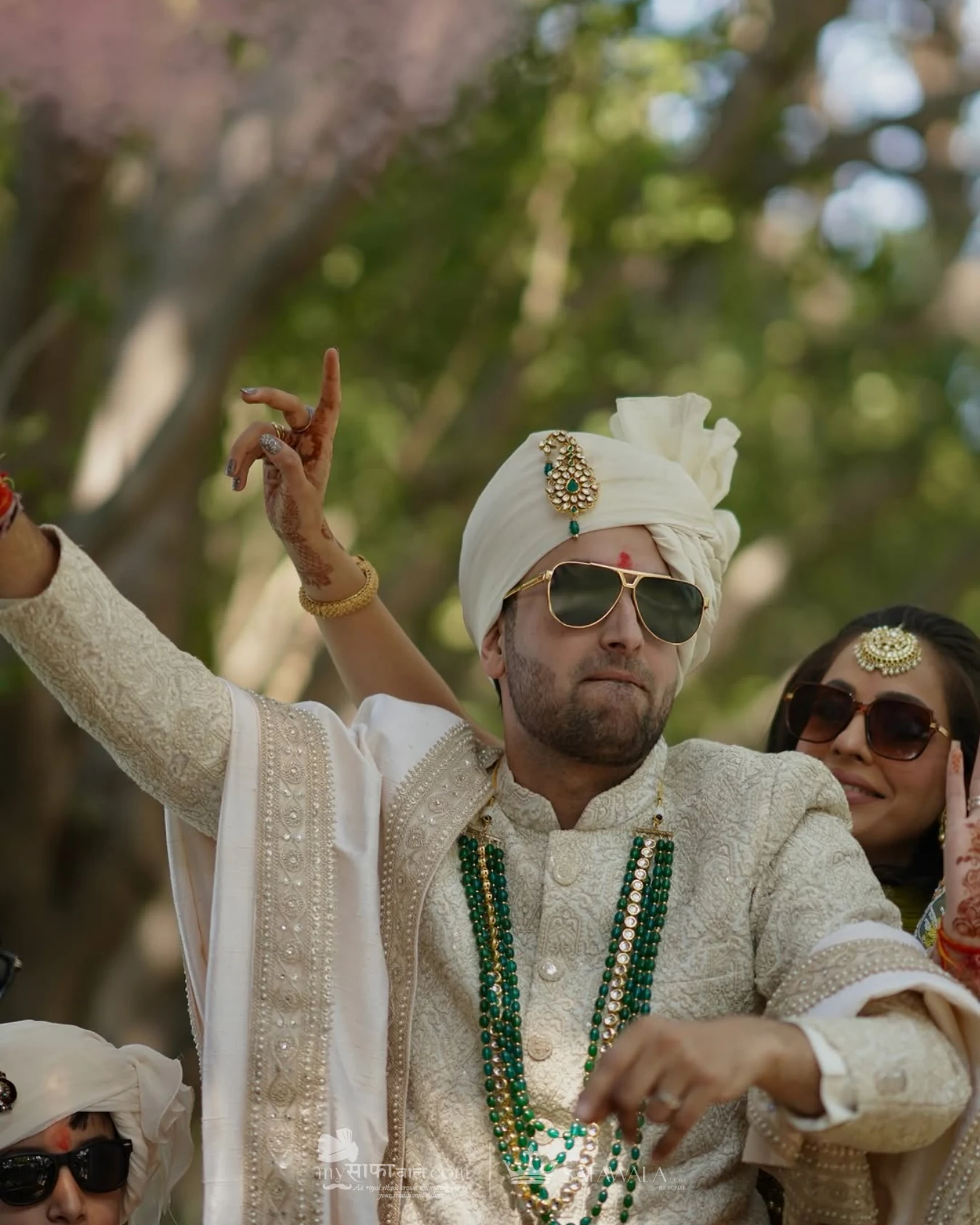 Groom in an ivory wedding safa with emerald jewellery for Akshi
